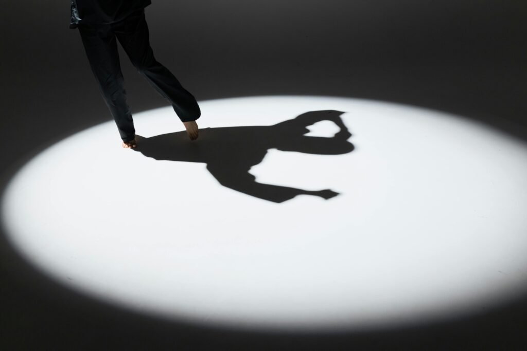 Shadow of a dancing figure in a spotlight, highlighting expressive movement and artistic grace.